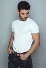 Muscle Strong Beautiful Stripped Male Model In Denim Blue Jeans With White T-shirt On Grey Isolated Font Background