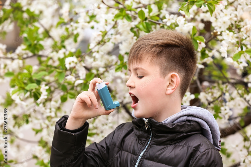Boy with inhaler having asthma attack on spring day