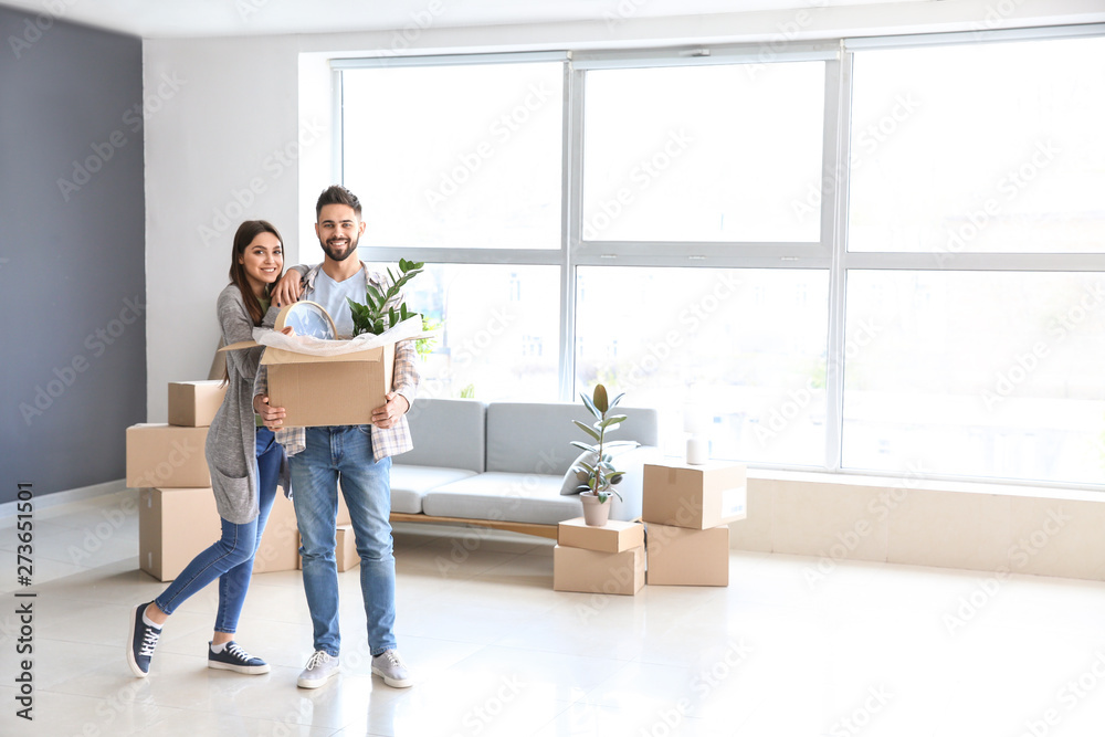 Young couple with belongings in their new house - obrazy, fototapety, plakaty 