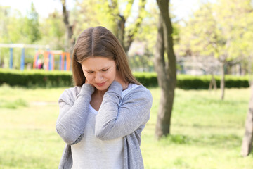 Wall Mural - Young woman suffering from neck pain outdoors