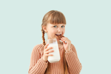 Wall Mural - Cute little girl with glass of milk and cookie on light background