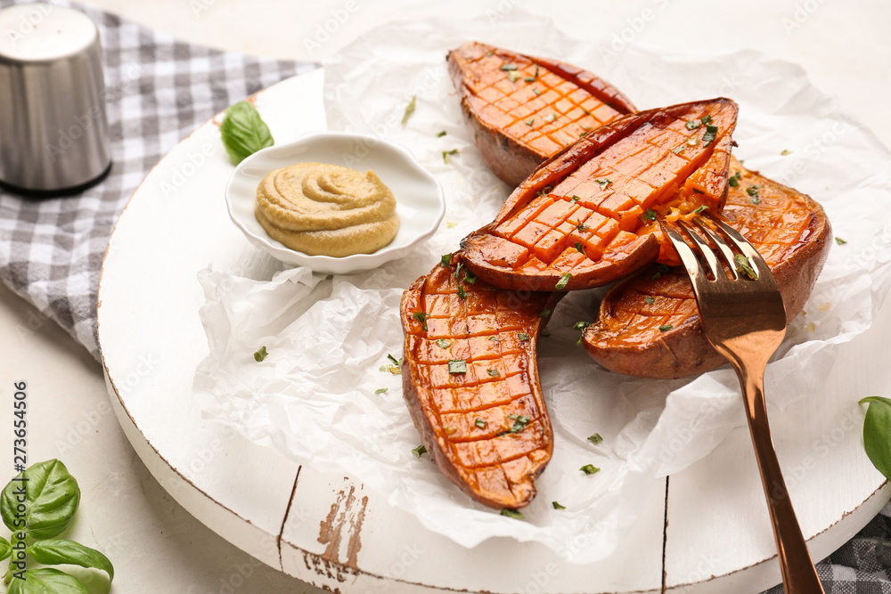 Board with tasty cooked sweet potato and sauce on table