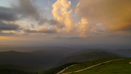 Wall Mural - Timelapse of clouds at sunset over mountain road,4k footage