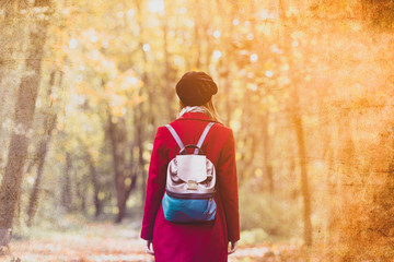 Wall Mural - woman in red coat and backpack resting in autum park