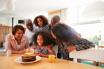 Multi-Generation Family Celebrating Granddaughters Birthday At Home With Cake And Candles