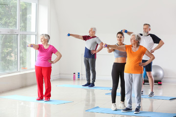 Elderly people training with instructor in gym