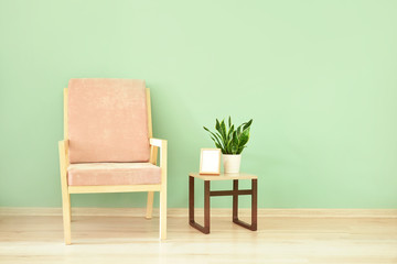 Modern armchair and table near color wall