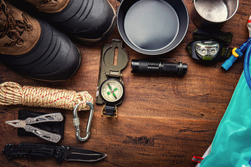 Outdoor travel equipment planning for a mountain trekking camping trip on wooden background. Top view - vintage film grain filter effect styles