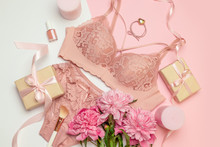 Female Elegant Pink Lace Bra And Panties, Pink Candles, Hair Tie, A Bouquet Of Beautiful Peonies, Nail Polish, Jewelry, Top View