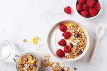 Greek Yogurt In Bowl With Raspberries And Muesli On White Table Top View. Healthy  Breakfast.