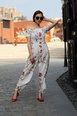 Asian Chinese model girl influencer street shot. Wearing white printed floral patterned jumpsuit.  Street view background.