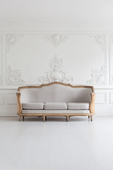 Luxurious bright Rococo interior with a large sofa and stucco on the walls. Selective focus.