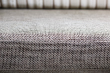 Closeup Of A Fragment Of A Beige Textile Sofa In The Room. Texture Of Expensive Fabric On Furniture