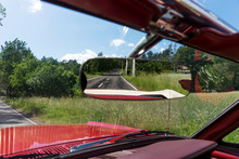 Asphalt road in the rearview mirror. Rear view mirror in the Cabriolet