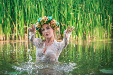 A fabulous, lake nymph in long white lace dress and wreath. Artistic Photography, Mysterious scene. European Witch . Fairytale