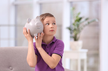 Poster - Little boy with piggy bank at home