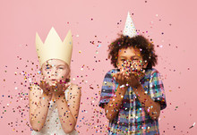 Waist Up Portyrait Of Two Children Blowing Glitter At Camera While Standing Against Pink Background, Copy Space