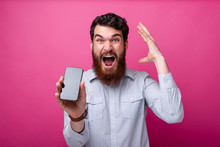 Blow Your Mind Concept. Young Bearded Man Showing Smartphone Blank Display, Gesturing With His Hand Near His Head.