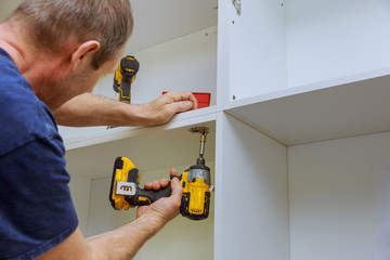 Wall Mural - Assembling furniture white in modern kitchen screws using screwdriver