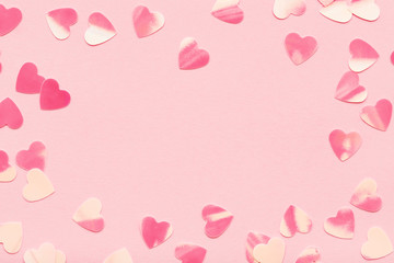 Wall Mural - Heart shape confetti on pink pastel holiday background. Festive frame, Valentine's Day. Flat lay, copy space.