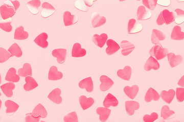 Wall Mural - Heart shape confetti on pink pastel holiday background. Festive abstract backdrop, Valentine's Day, Love. Flat lay.