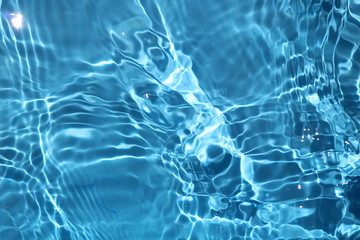 blue and bright water surface with sun refection in swimming pool for background