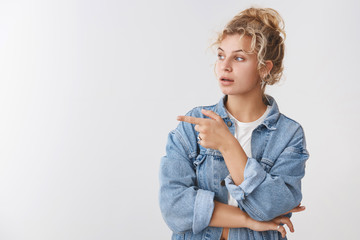Wall Mural - Curious attractive female blond customer pick furniture asking advice shop assistant turn point left interested questioned gazed sideways intrigued what happening, posing white background