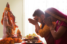 Husband And Wife Praying With Hands Joined In Front Of Ganesha Idol On The Occasion Of Ganesh Chaturthi	