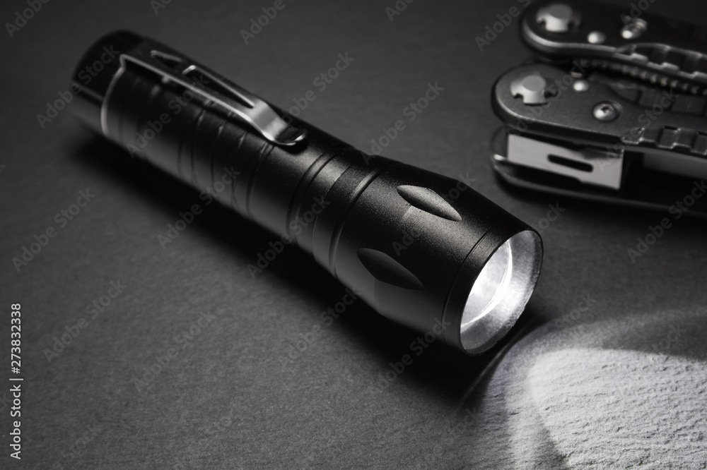 black flashlight on the stone surface. Tools for work, search and tourism .. - obrazy, fototapety, plakaty 