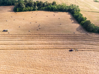 Nature and landscape, aerial view of fields with tractor with round baler and tractor with a rake, machines for collecting and pressing hay. Field with swaths ready to be transformed into round bales