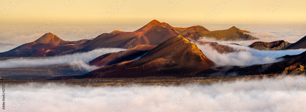 Volcanoes in the Timanfaya national park on Lanzarote. Volcanoes rising out of the clouds - obrazy, fototapety, plakaty 
