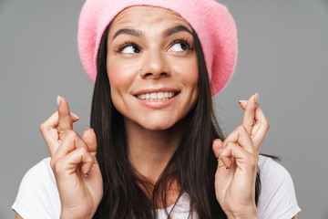 Wall Mural - Photo closeup of gorgeous pretty woman in basic t-shirt and beret smiling and keeping fingers crossed for good luck