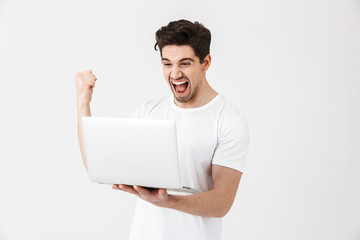 Poster - Happy excited young man posing isolated over white wall using laptop computer make winner gesture.