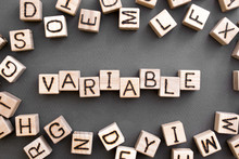 The Word Variable Wooden Cubes With Burnt Letters, Variable Life, Gray Background Top View, Scattered Cubes Around Random Letters