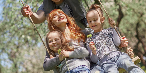 big happy family swinging on garden swings