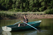 Young Man Floats On A Wooden Boat With Oars