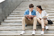 © Drobot Dean - Amazing loving couple students colleagues outdoors outside on steps reading book writing notes studying.