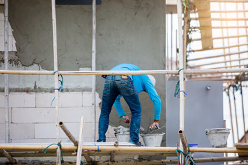 plasterer in blue working uniform plastering the wall of house building site. hands plasterer tools. industrial worker with plastering tools.