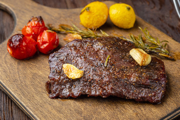 Grilled rib eye  steak with spices  served on a wooden board with baked vegetables