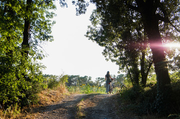 Girl on a sunset in a forest. Golden light. Green trees and sunset