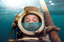 Portrait Of Man In Old Diving Suit And Helmet Under Water. Funny Diver In Retro Equipment With Water Inside His Helmet .