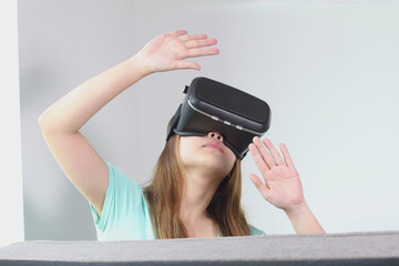 Young woman wearing virtual reality glasses at home.