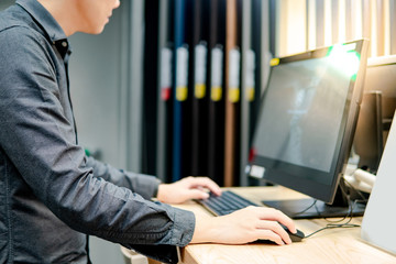asian man clicking computer mouse using desktop computer in furniture store. interior material desig