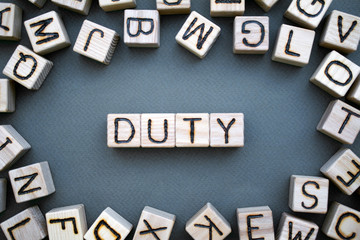 Fototapete - the word duty wooden cubes with burnt letters, duties of people, gray background top view, scattered cubes around random letters