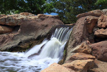 Artificial waterfall in Piney Creek East Park, Colorado, at bright sunny day. Long exposure.