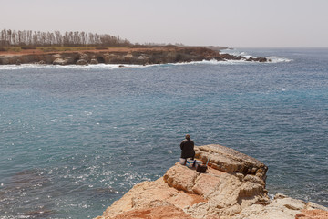 Man fishing at the sea rocky shore in Cyprus