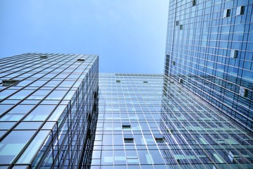 Bottom view of modern skyscrapers in business district against blue sky