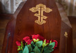 © Evgeniya - A coffin with a bouquet of red roses on the lid. Selective focus. The funeral.