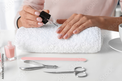 Woman applying nail polish at table, closeup. At-home manicure