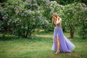  beautiful young happy girl in an incredible dress resting outdoors,woman walking in the park amid blooming lilacs